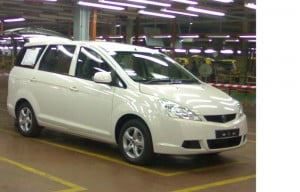 Proton MPV warna putih dengan latar belakang seperti dalam kilang
